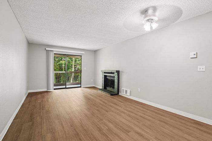 Living room at Creekwood with a fireplace with black tile around it and a sliding glass door leading to the patio