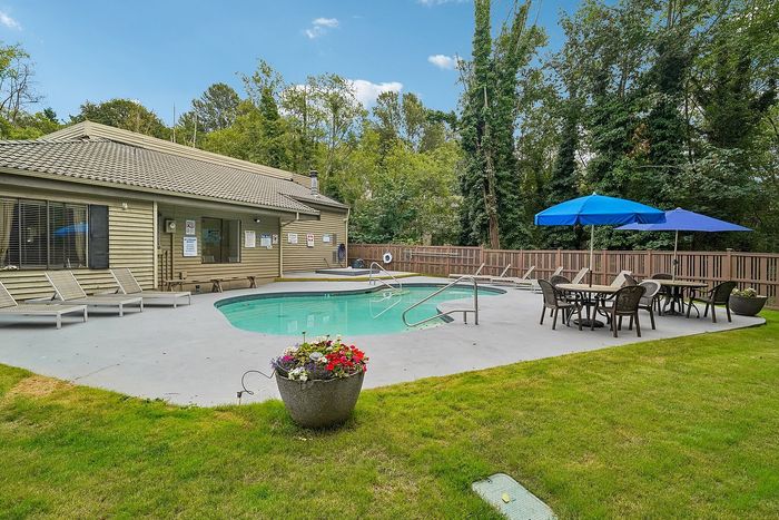 Pool at Creekwood with lounge chairs and tables with umbrellas