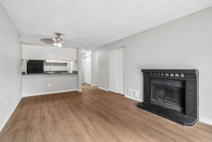 Living Room at Creekwood with a fireplace with black tile around it and a ceiling fan