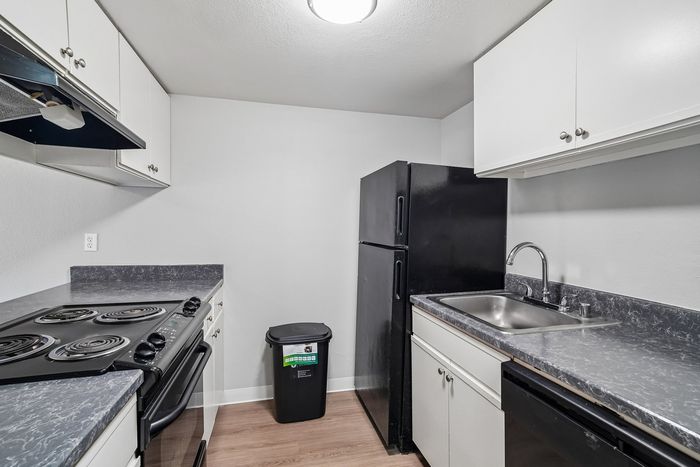 Kitchen at Creekwood with black appliances and grey marbled countertops