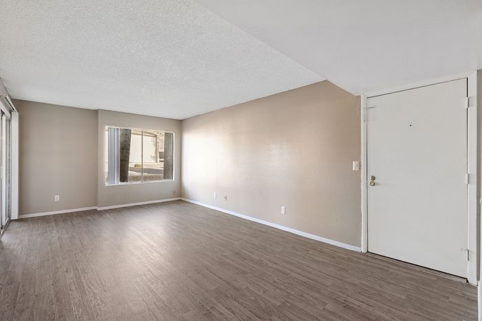 Open living area featuring neutral paint, wood-style floors, and natural light from a large window.