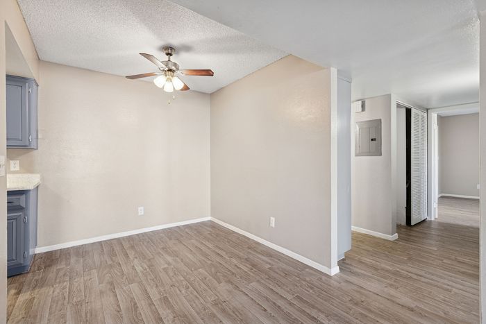 Dining area with wood-style floors and a lighted ceiling fan near the kitchen entrance.