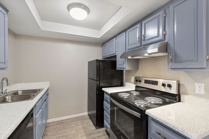 Kitchen at Solaris at Shadow Mountain with blue cabinetry, white counters, and black appliances.