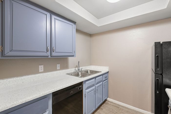 Modern kitchen featuring blue cabinets, white countertops, and a double stainless steel sink.