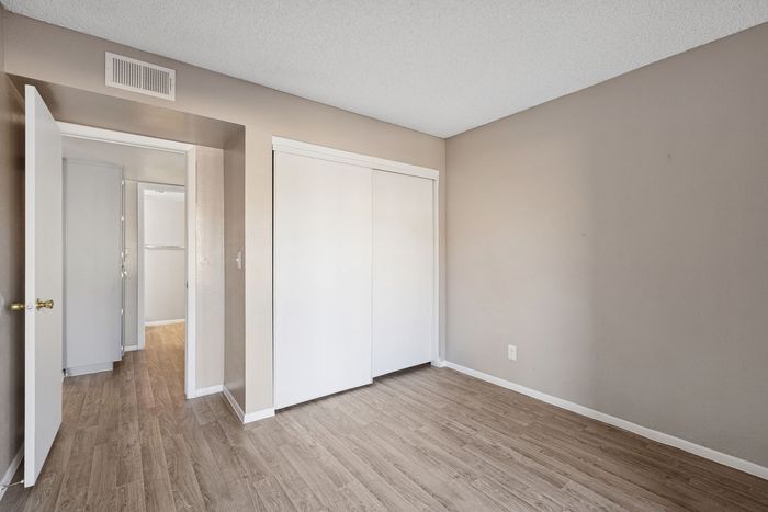 Bedroom featuring neutral walls, wood-style flooring, and a large sliding door closet.