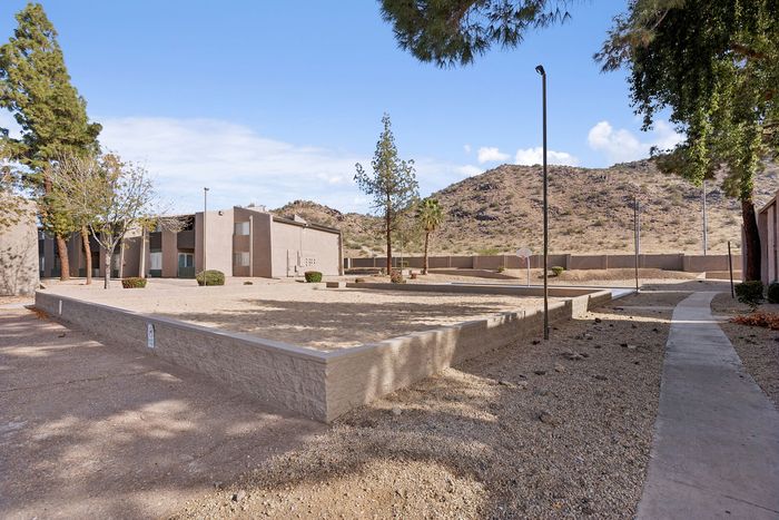 Outdoor sand volleyball court and basketball hoop with mountain views.