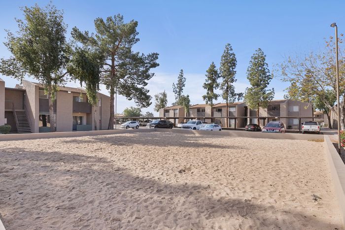 Sand volleyball court at Solaris at Shadow Mountain with surrounding trees and parking area.