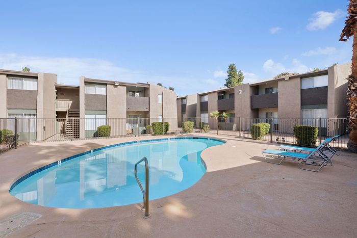 Gated swimming pool at Solaris at Shadow Mountain with blue lounge chairs and pool deck.