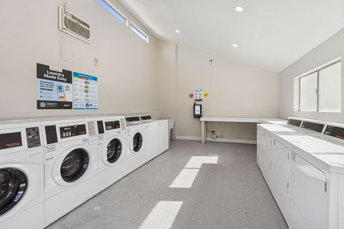 Bright laundry facility with rows of white front-loading washing machines.