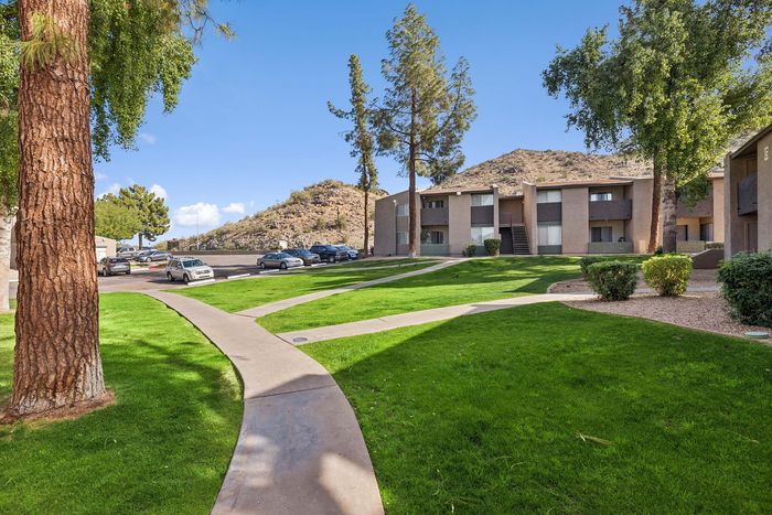 Winding sidewalk through a lush green lawn with mountain views in the background.