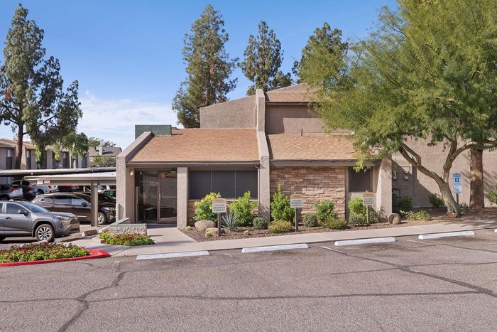 Leasing office exterior showing resident parking and stone-accented architecture.