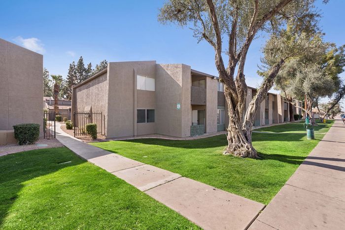Two-story apartment buildings with stucco exteriors and mature landscaping.