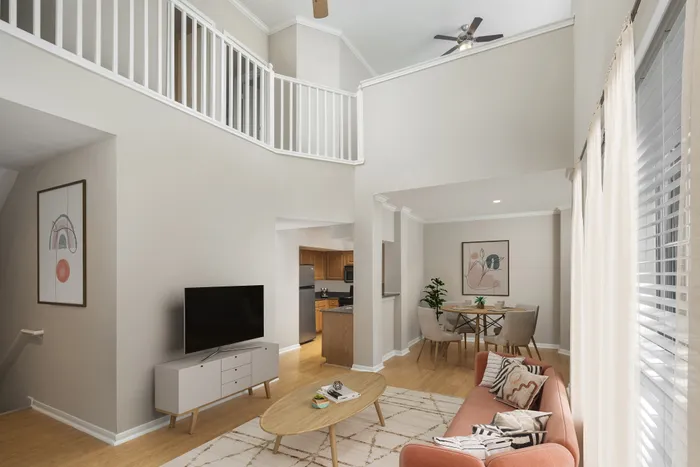 Chic two-story living room with vaulted ceiling, elegant wood flooring, stylish furniture, and abundant natural light.