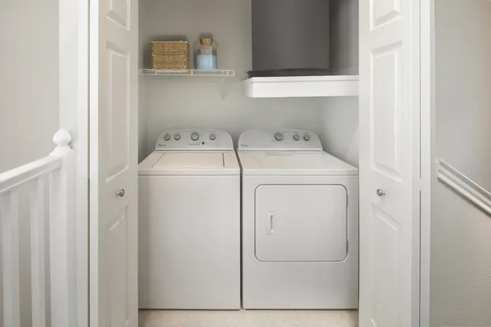 Bright utility closet with modern washer and dryer, complemented by sleek shelving for organized laundry essentials.
