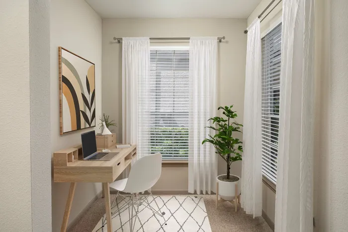 Chic and serene home office space with natural light, featuring a modern wooden desk, elegant white chair, vibrant indoor plant, and abstract wall art.