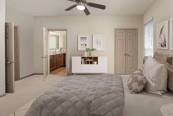 Elegant bedroom with plush bedding, modern ceiling fan, and spacious en-suite bathroom featuring luxurious cabinetry.
