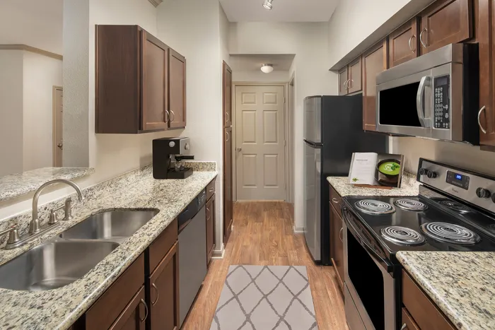 Modern kitchen with elegant granite countertops, stainless steel appliances, and warm wood cabinetry.