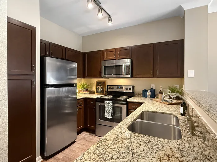 Modern kitchen with sleek stainless steel appliances, rich wooden cabinetry, and elegant granite countertops.