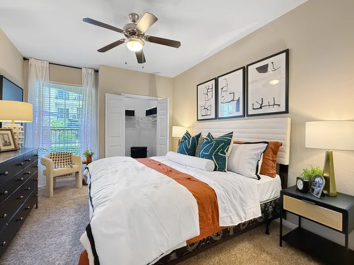Inviting bedroom with elegant decor, featuring a cozy bed, stylish artwork, and abundant natural light from a large window.
