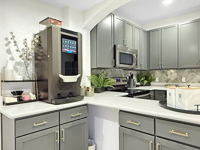 Modern kitchen with sleek gray cabinetry, stainless steel appliances, and a stylish coffee station setup.