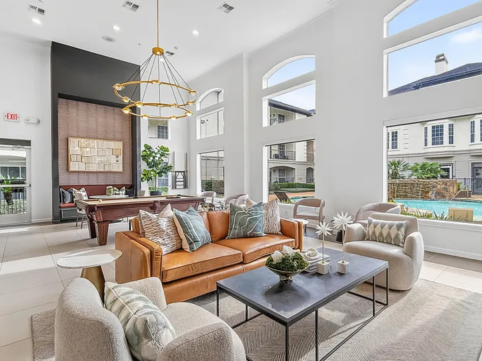 Luxurious apartment lobby with modern decor, plush seating, and large windows overlooking a serene pool area.