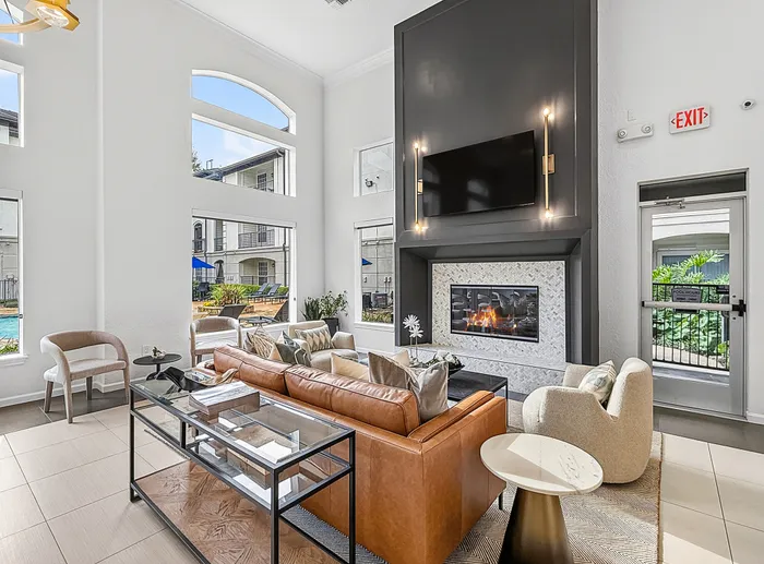 Bright and inviting living area featuring a modern fireplace, plush seating, and large windows showcasing poolside views, perfect for relaxing and entertaining.