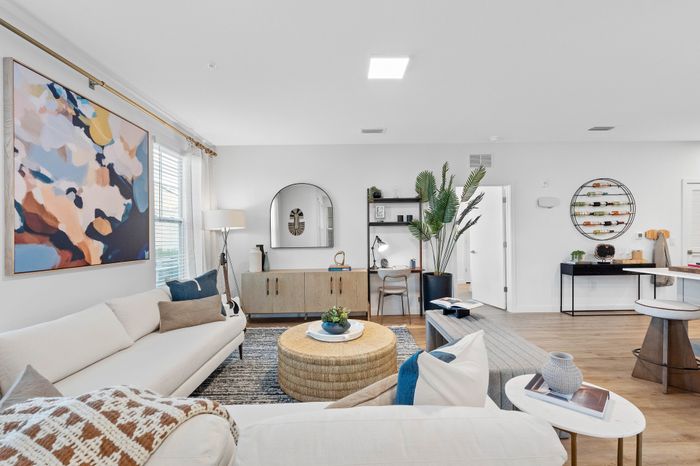 Beautifully designed living room with modern decor, stylish couch, artistic wall painting, and cozy workspace. Ideal for chic urban living.