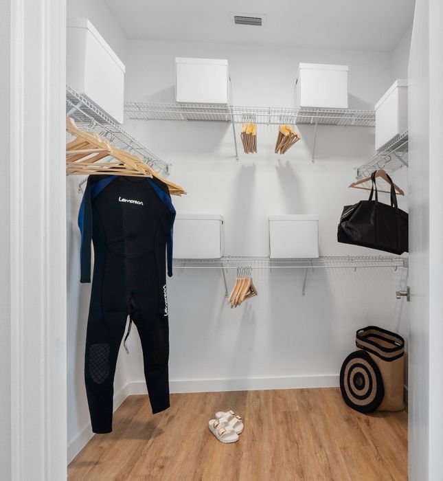 Modern walk-in closet featuring ample shelving, hanging storage, and elegant wooden flooring.