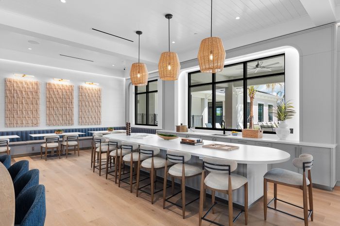 Elegant dining area with modern design, featuring a long white island with sleek chairs, stylish pendant lighting, and a cozy seating nook.