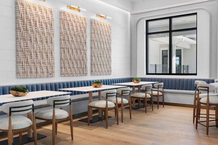 Chic dining area with elegant tables, stylish chairs, and modern decor, featuring a large window and unique wall art.