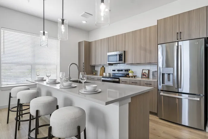 Modern kitchen with sleek stainless steel appliances, elegant pendant lighting, and a stylish breakfast bar with plush seating.