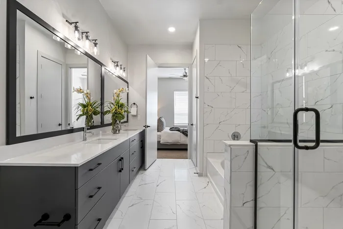 Luxurious modern bathroom with elegant double vanity, large mirror, sleek cabinetry, and spa-like shower in premium apartment.