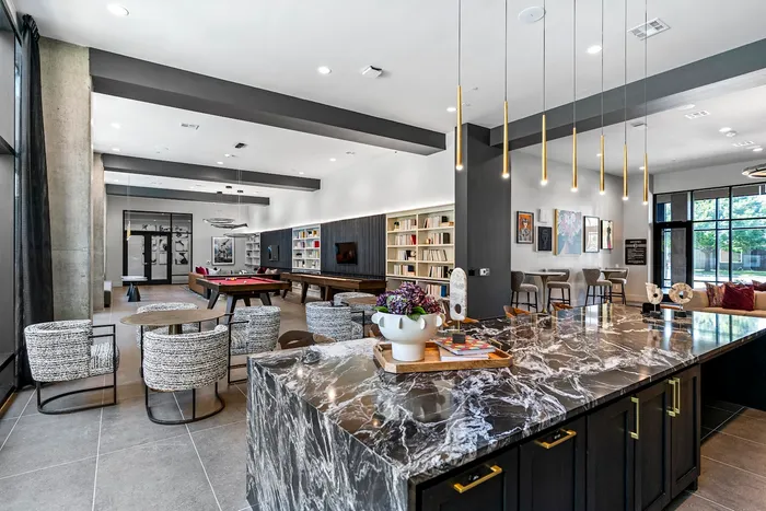 Luxurious and modern communal space featuring a marble countertop, stylish seating, pool table, and shelving with books, offering a perfect blend of elegance and comfort.