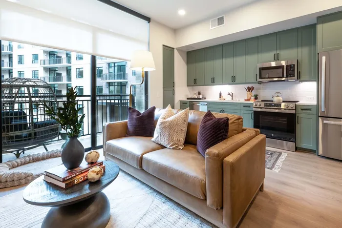 Elegant living area with a cozy leather sofa, chic d&eacute;cor, and a modern kitchen in a stylish city apartment.