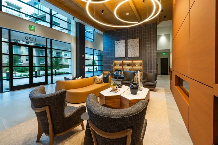Elegant apartment lobby with stylish seating, modern light fixtures, and large windows offering a bright, welcoming atmosphere.