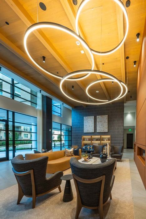 Sophisticated modern lounge with contemporary circular lighting, plush seating, and expansive windows providing natural light.