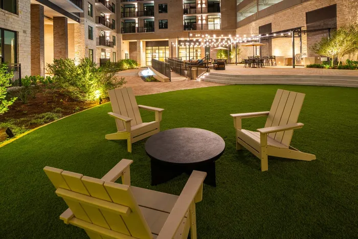 Modern apartment courtyard with stylish outdoor seating and ambient string lights, offering a perfect space for relaxation and entertainment.