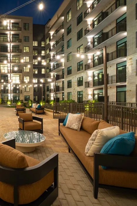 Chic apartment complex with an illuminated outdoor seating area featuring cozy sofas and elegant lighting, perfect for relaxed evening gatherings.