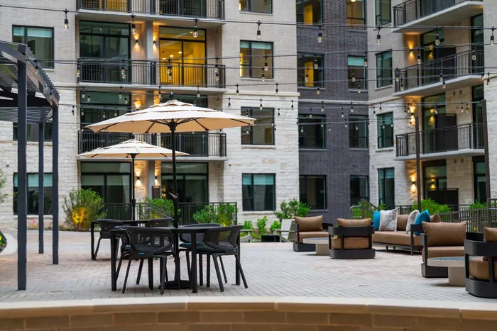 Inviting courtyard view with elegant seating areas, string lights, and modern apartment facade.
