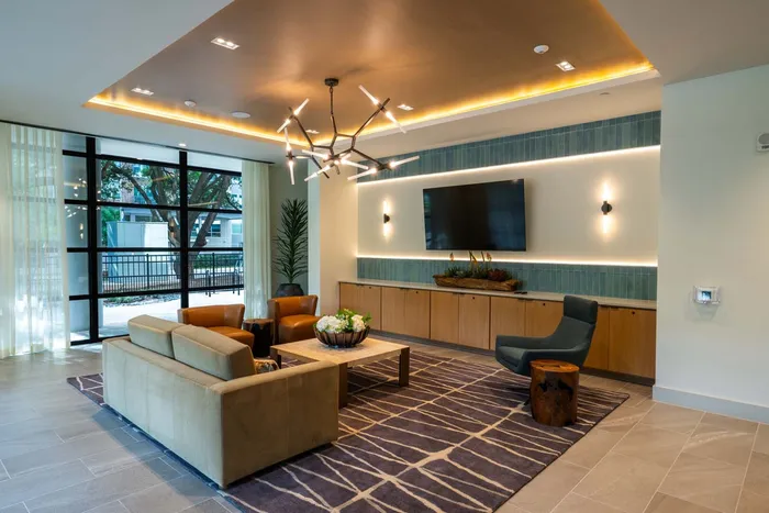 Modern apartment lounge with elegant lighting, cozy seating, and floor-to-ceiling windows for natural light.