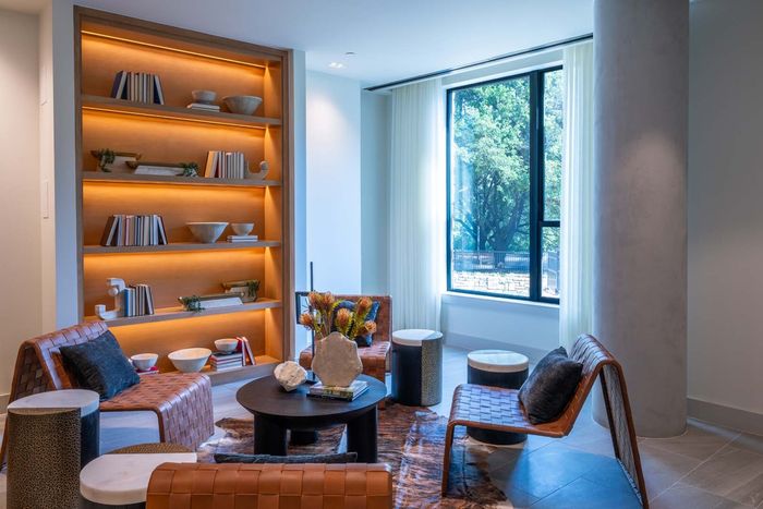 Chic modern living space with elegant leather chairs, a stylish bookshelf, and a large window for natural light.