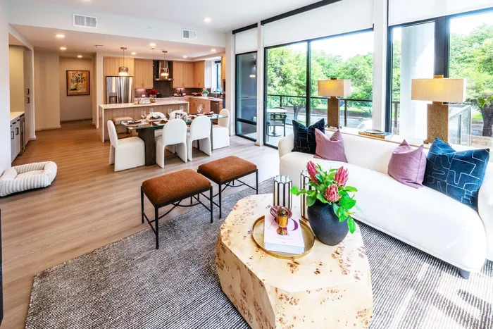 Elegant open-plan living room and kitchen with stylish decor, large windows offering scenic views, and a welcoming dining area.