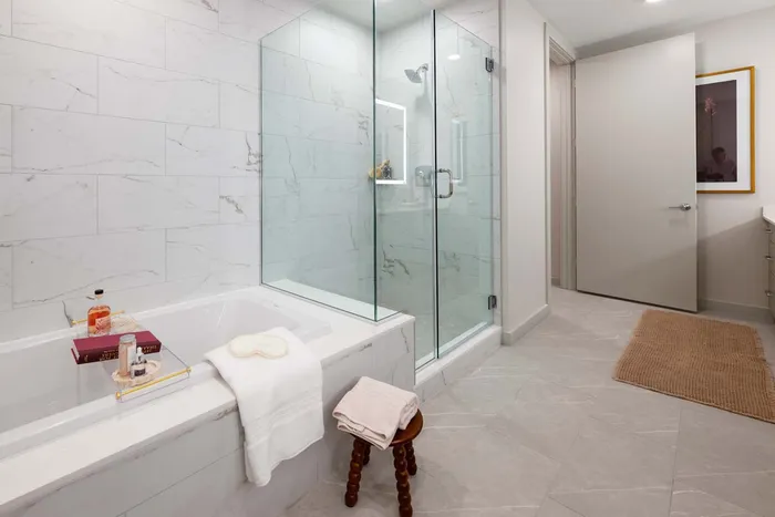 Luxurious bathroom featuring a modern glass-enclosed shower and an elegant soaking tub with marble tile accents.