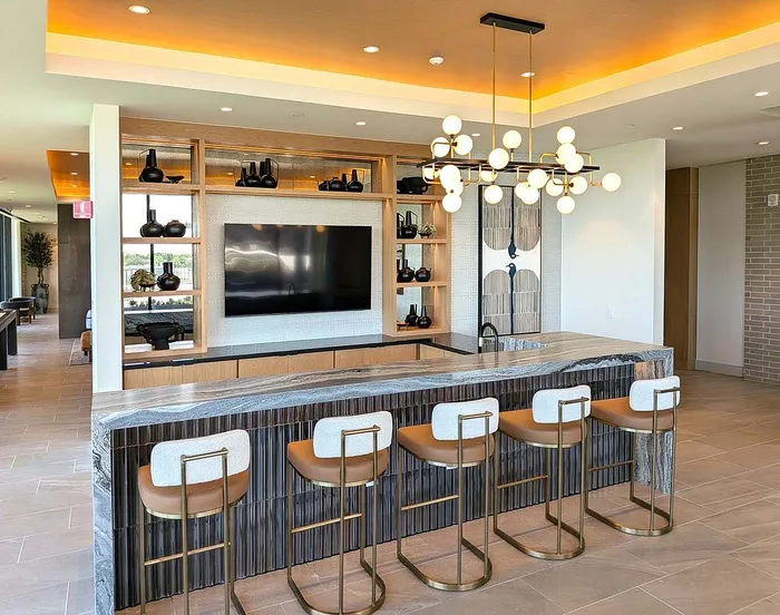 Chic apartment clubhouse with a sleek marble island, designer seating, and modern lighting accents.