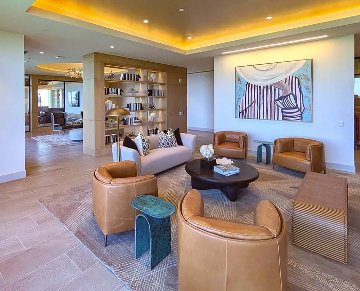 Elegant modern living area featuring stylish leather chairs, a contemporary art piece, and ambient lighting in a spacious setting.