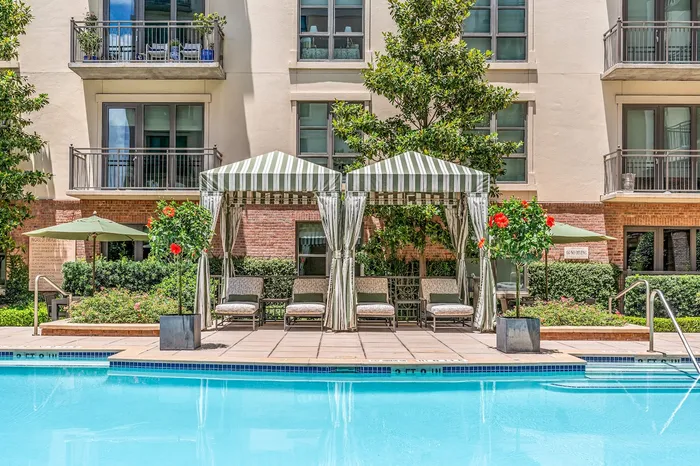 Luxurious apartment courtyard featuring a sparkling pool, elegant cabanas, and lush landscaping for a relaxing outdoor experience.