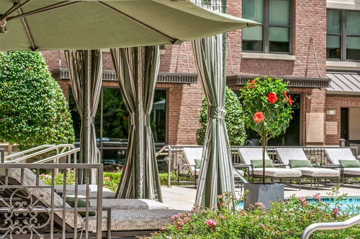 Luxurious outdoor pool area with elegant lounge beds, blooming flowers, and stylish cabanas, perfect for relaxation and enjoying sunny days.