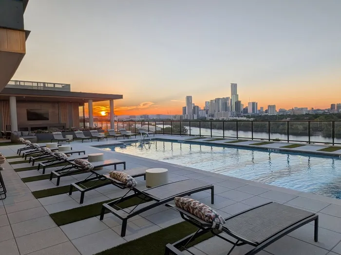 Luxurious rooftop pool with stunning sunset views over a vibrant city skyline, perfect for relaxation and enjoyment.