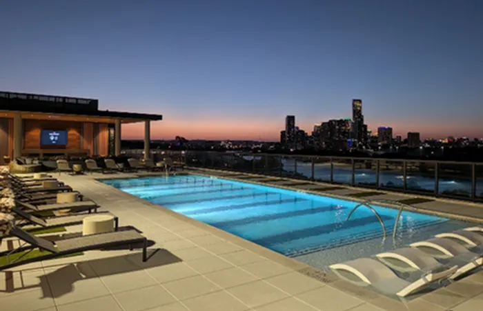 Stunning rooftop pool with city skyline views at sunset, offering luxurious relaxation and modern amenities.