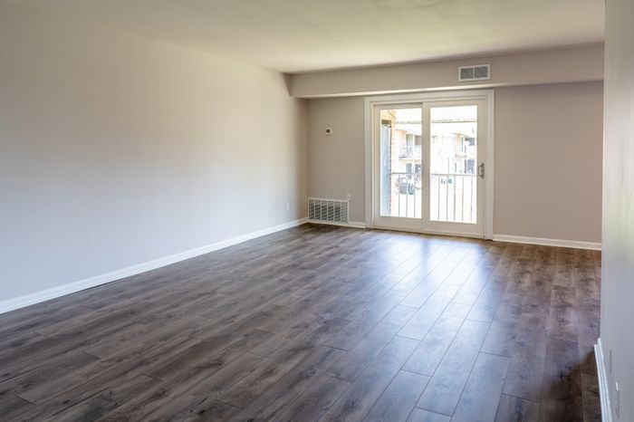 Living room with wood-look floors and sliding glass door at Woodcrest Village Apartments.